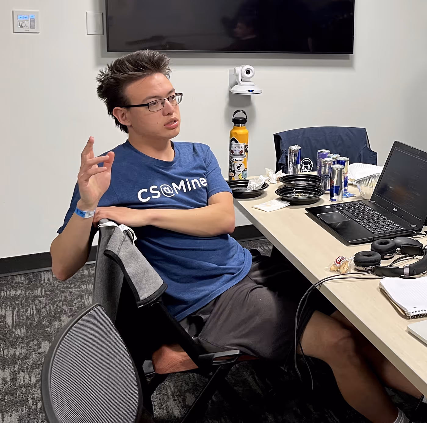 I lean back in my chair with one hand in the air. I am surrounded by many cans of Red Bull and empty plastic food containers.