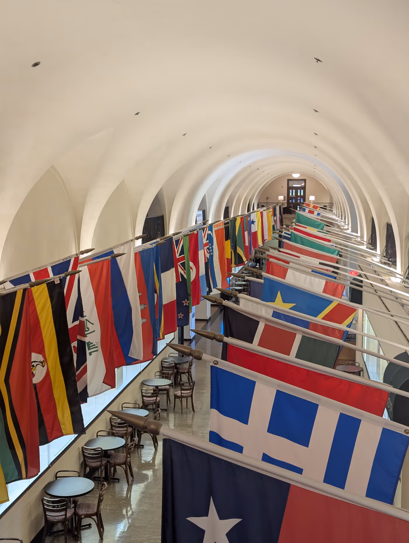 "a hallway lined with hundreds of flags on other side"