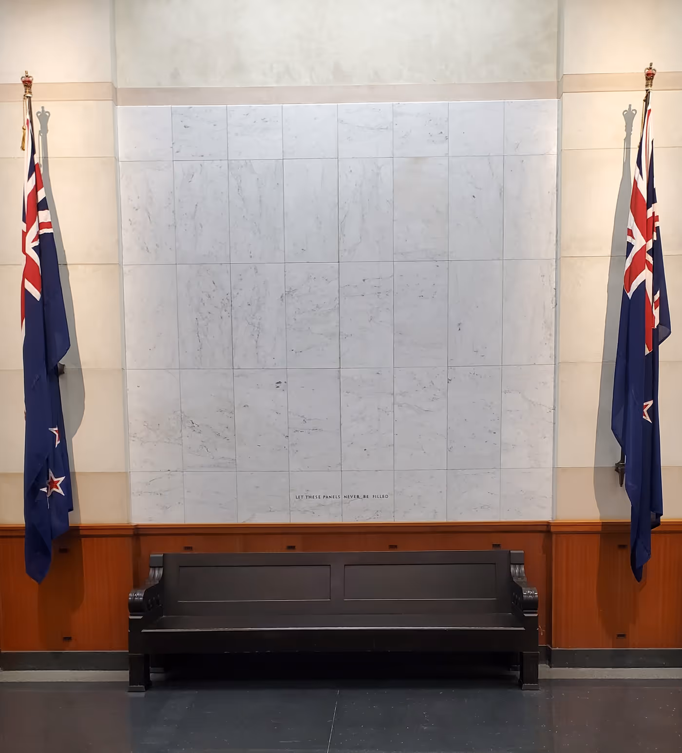 a wall of empty tiles with an inscription on the bottom reading, "Let these panels never be filled"